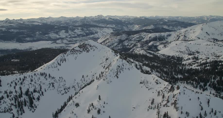 Aerial view of some snow covered mountains on a cloudy day