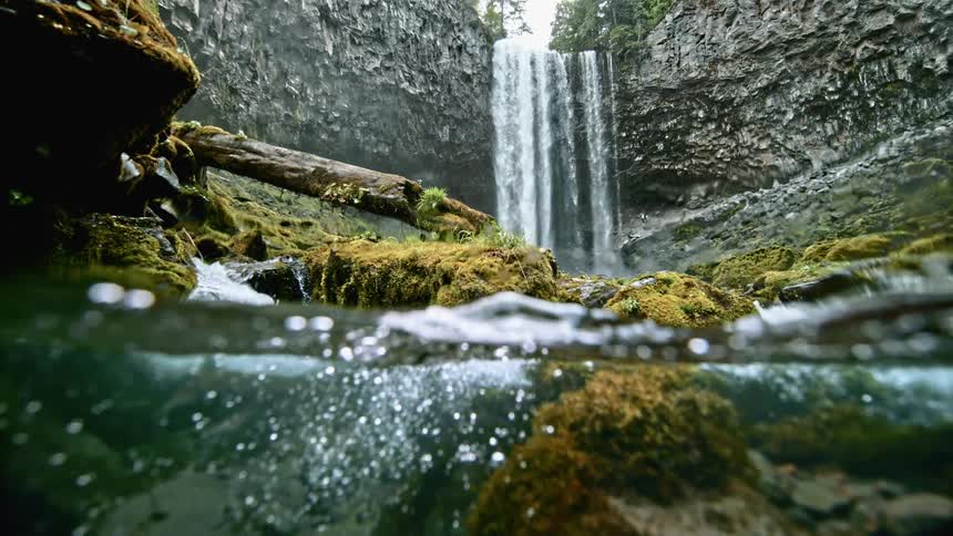 A waterfall cascades down the side of a cliff and feeds into the river below