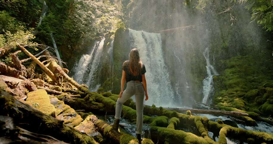 Woman watching a waterfall from bottom of the canyon