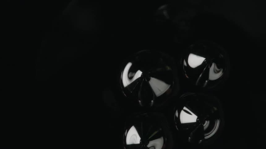 A few small pointed bubbles of liquid emerge from the surface of a dark black liquid