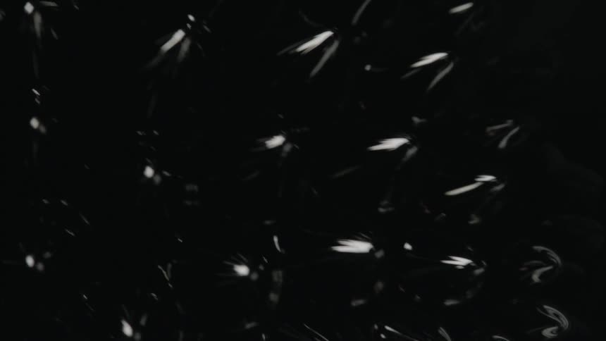 Small spikes form from the surface of a black but shiny ferromagnetic fluid