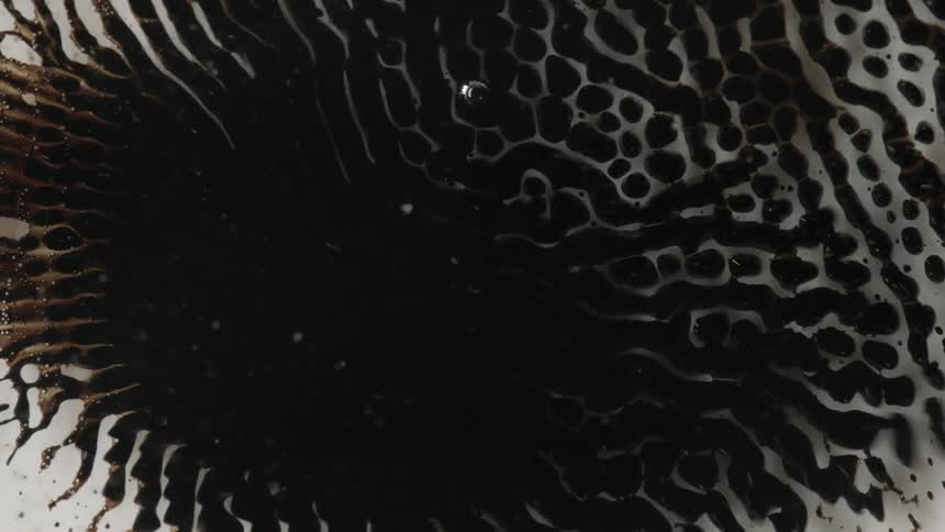 Magnetic fluid moves over a clear surface leaving a trail of dark liquid in its wake
