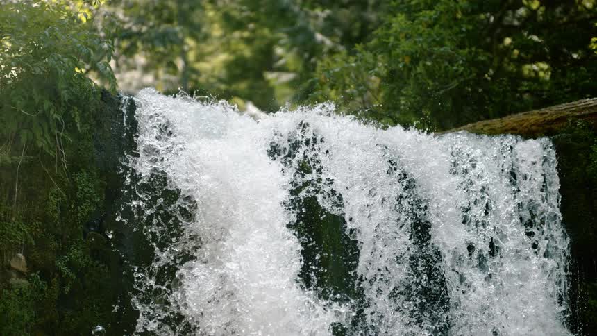 Turbulent water rushes over a small waterfall