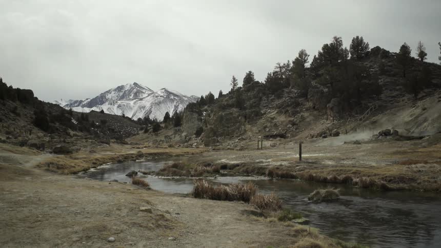 A small stream flows from a snow covered mountain in the distance