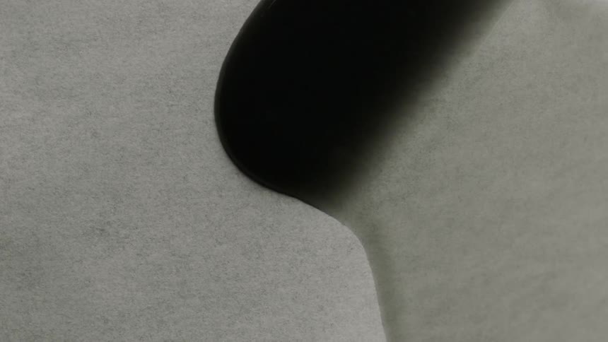 A wave of dark liquid pours across a table