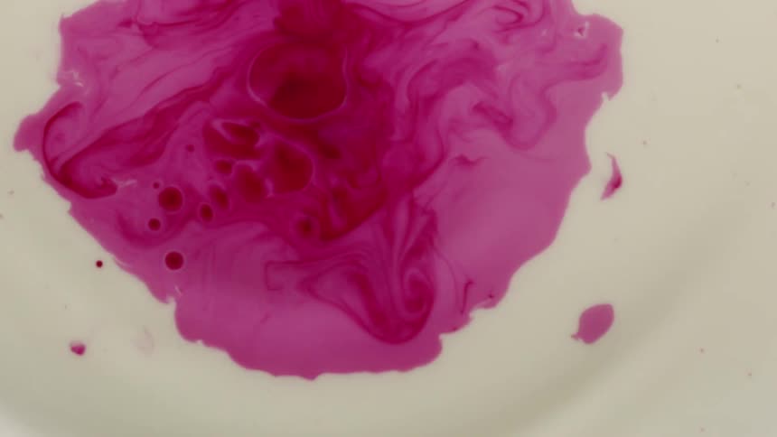 Drops of pink paint fall into a vat of white paint
