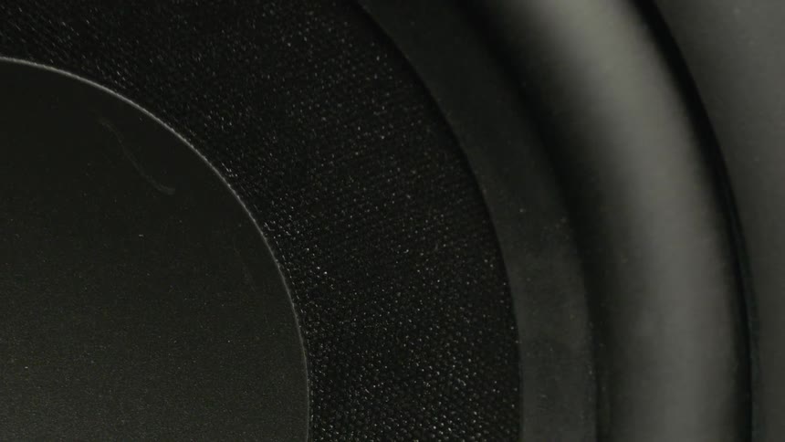 A close up of a stereo speaker shows the surface vibrating rapidly