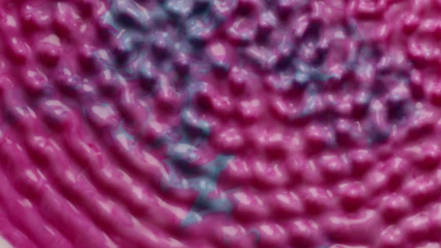 Radial ripples begin to propagate across the surface of a thick magenta and green liquid that resembles paint