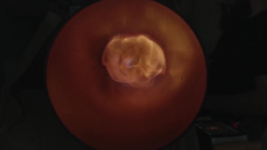 A fire burns and the flame fills the metal cylinder that it is confined in