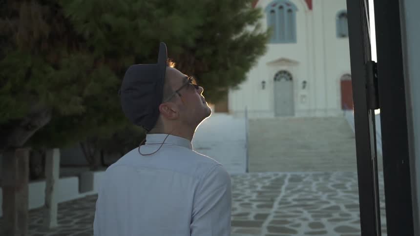 A man walking on a cobblestone path that leads to a church during a sunset