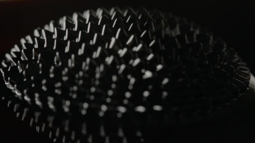 A ferrofluid bounces and moves on a dark surface