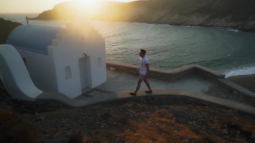 Man walks to small church building bordering beach