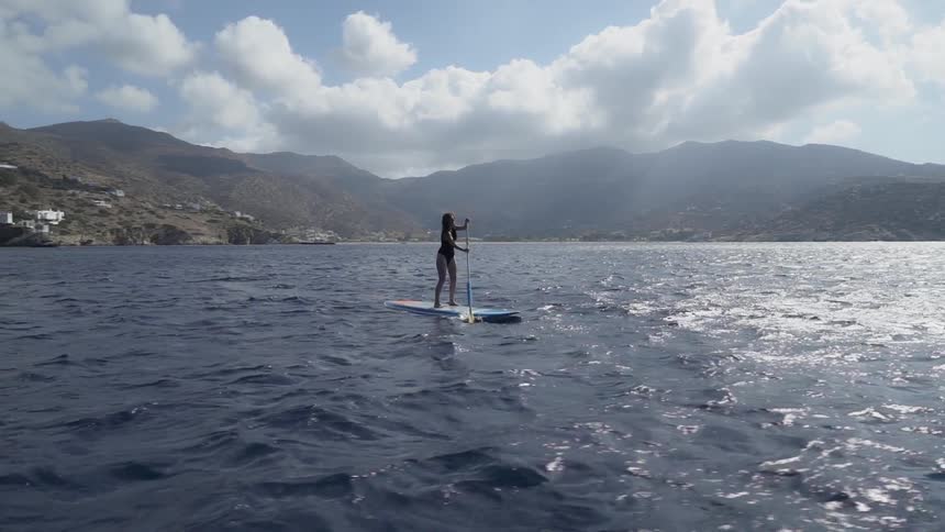 A woman paddling while on a surfboard