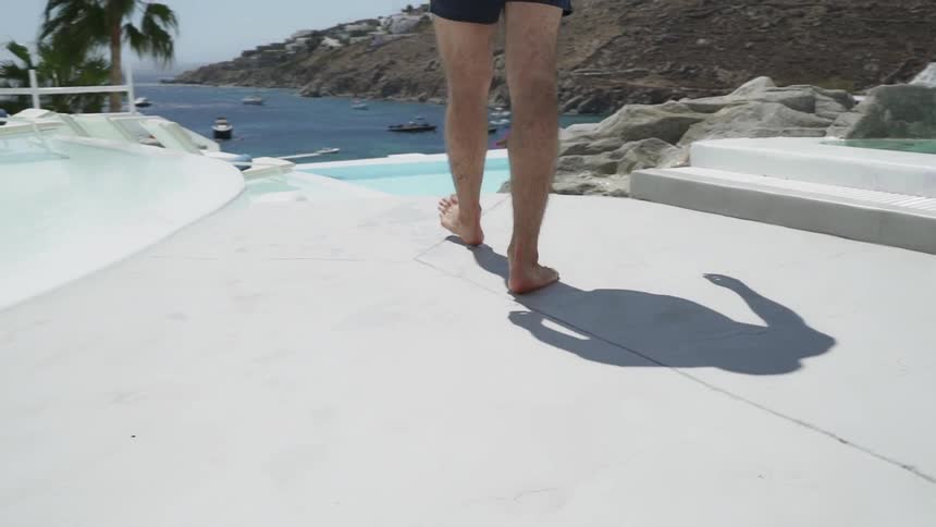 A person walks down steps at an ocean side resort by a pool