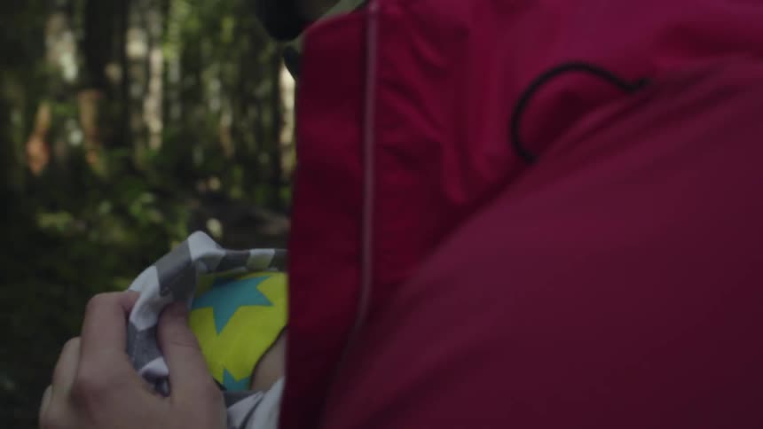 A baby is cradled and rocked by his mother outside in the forest
