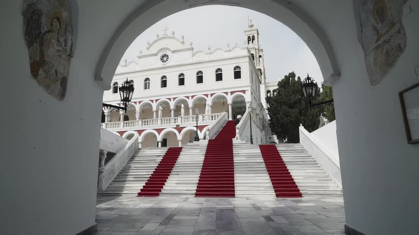 A large red carpet staircase leads to a white mansion