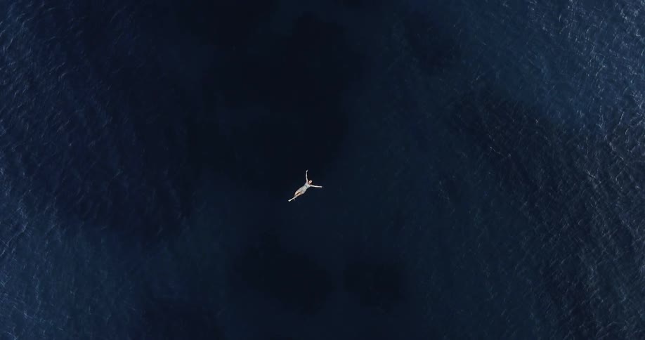 Woman floats in the middle of deep blue ocean