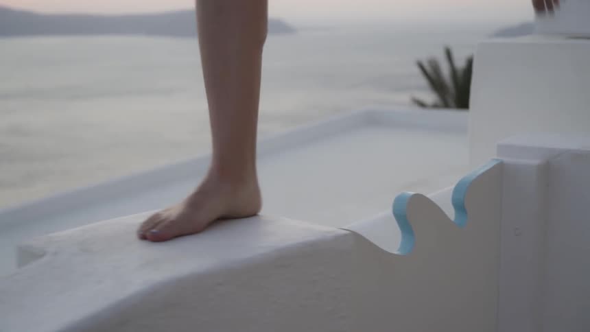 A woman walks along a ledge