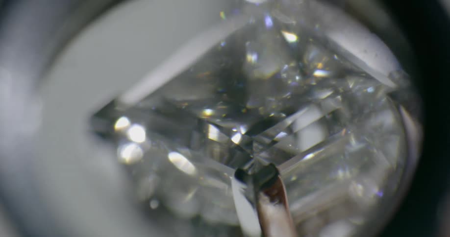A person looks at a diamond under a magnifying glass