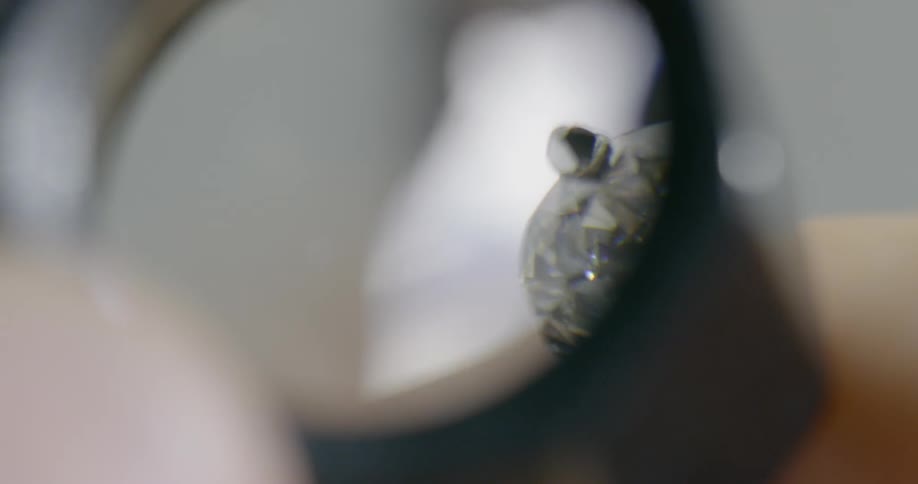 Someone looks at a diamond under a magnifying glass