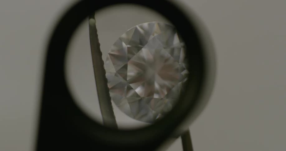A person looking at a diamond with a magnifying glass
