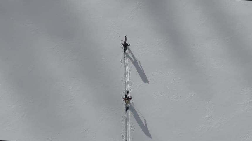 Aerial of cross country skiers trekking through an open field of snow