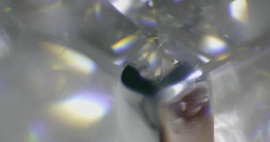 Light is refracting off of the numerous surfaces of a clear glassy gemstone