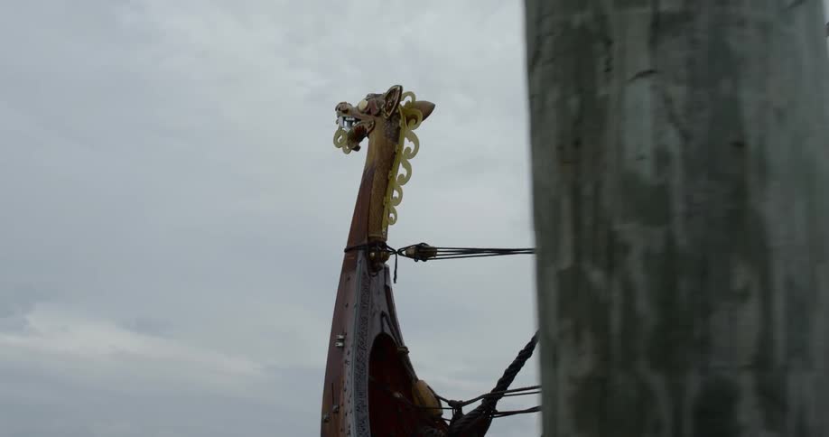 The bow of a wooden sailboat is carved to be the head of a dragon