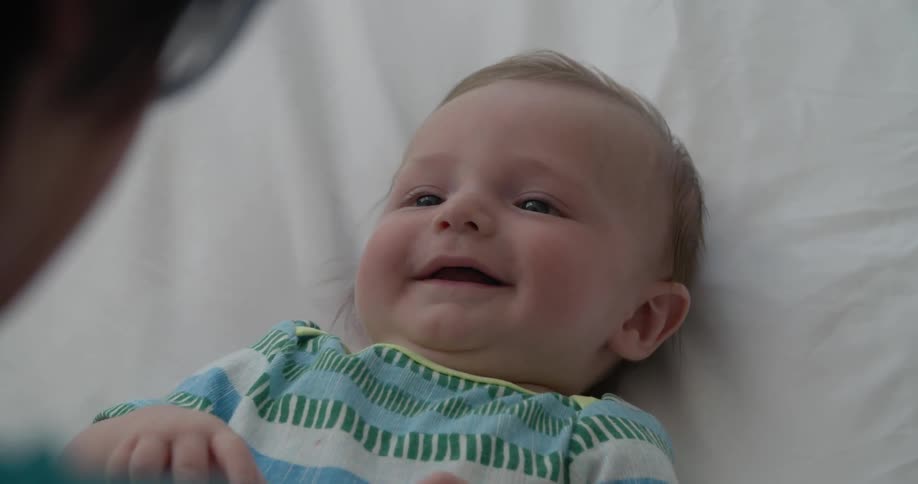 A baby is smiling and laughing at a person