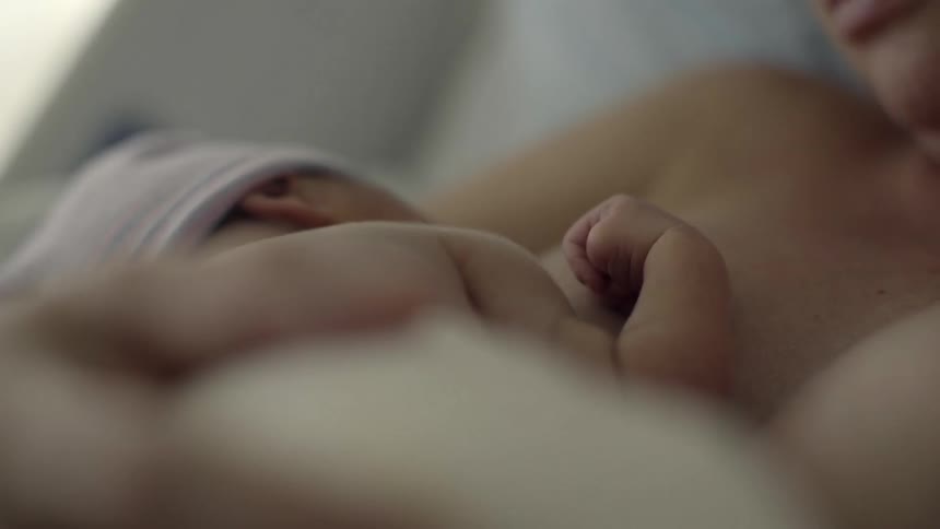 A woman is holding a baby as it sleeps