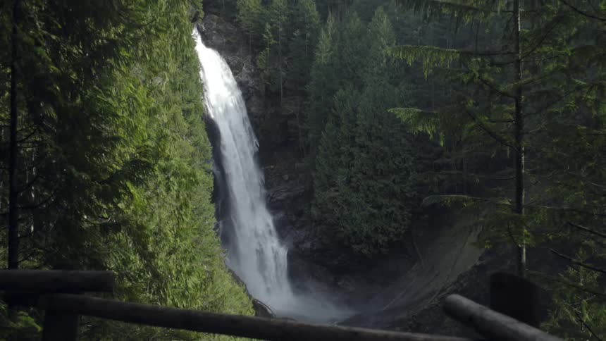 A waterfall gushes over a cliff in the woods