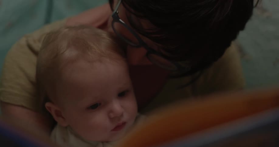 A woman holds a baby and reads it a book