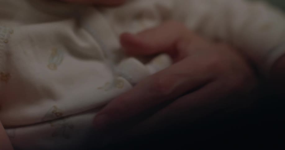 A woman rests her hand on a baby's stomach