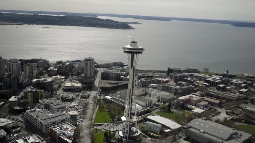 Aerial view of buildings and a tower by the water on a cloudy day