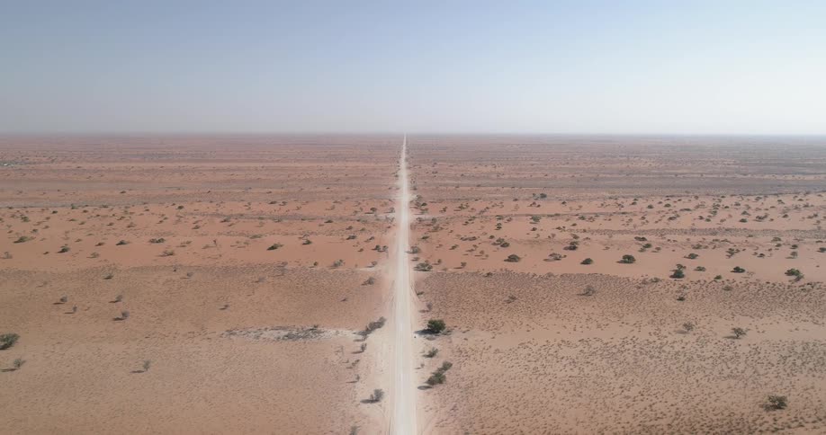 A dirt road in the middle of a barren field