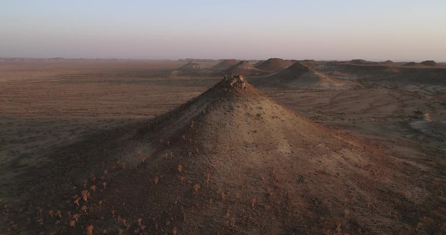Bare earth hills edge the desert under a clear blue sky