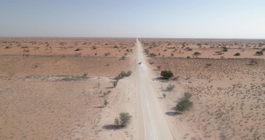 A vehicle driving down a dirt road in the desert