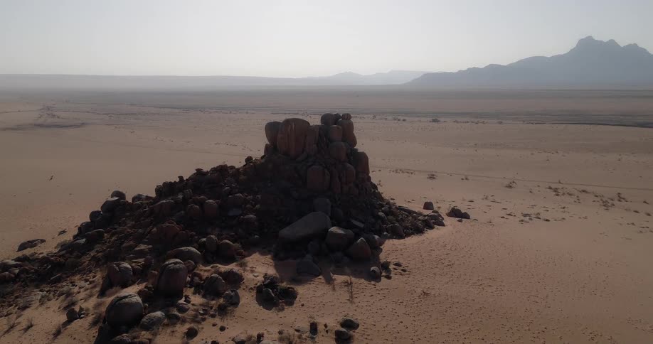 Piles of rocks in desert bordering mountains