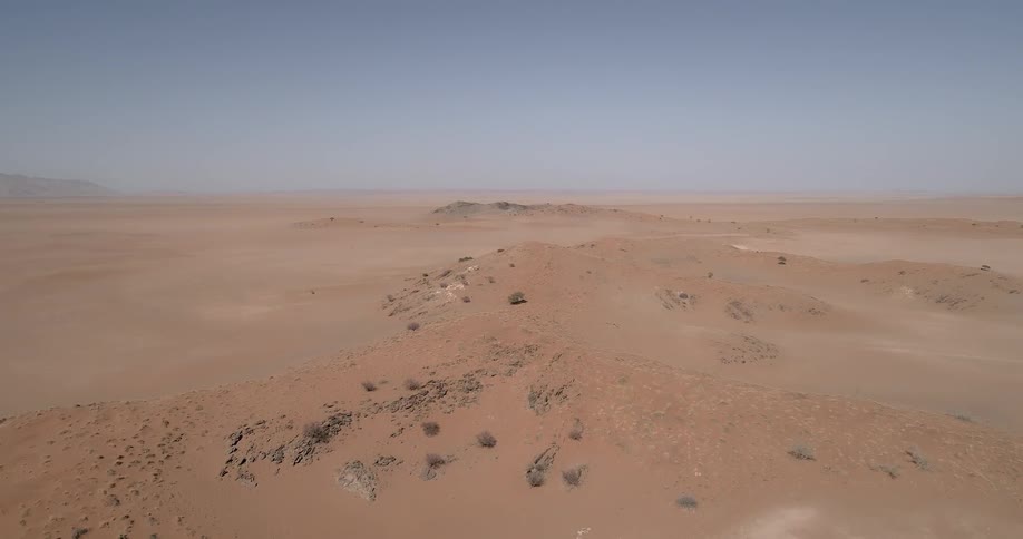 A sandy desert with the sky in the background