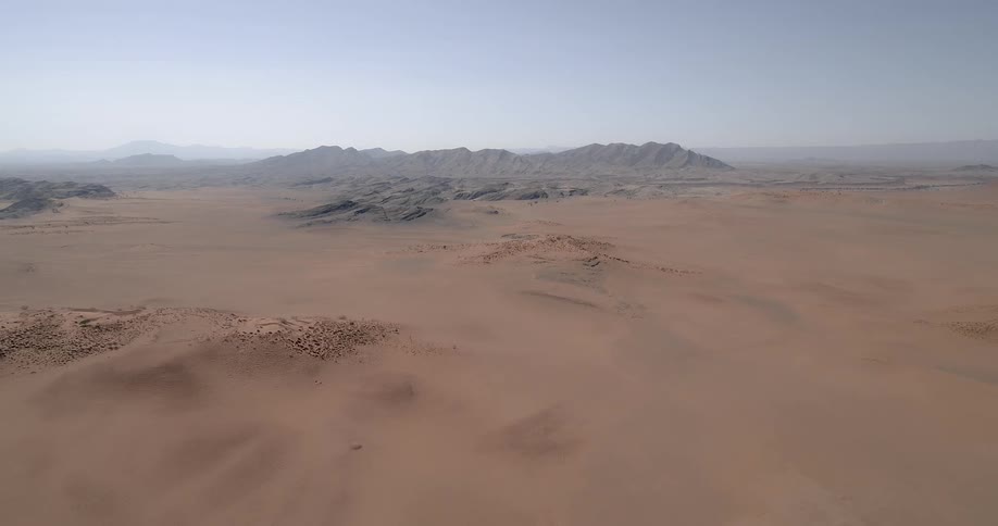 Sand stretches out before mountains