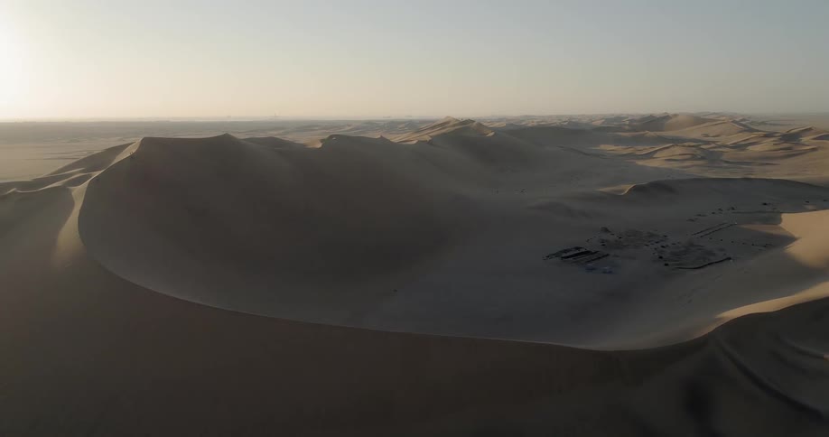 A large sandy desert is filled with numerous windswept sand dunes