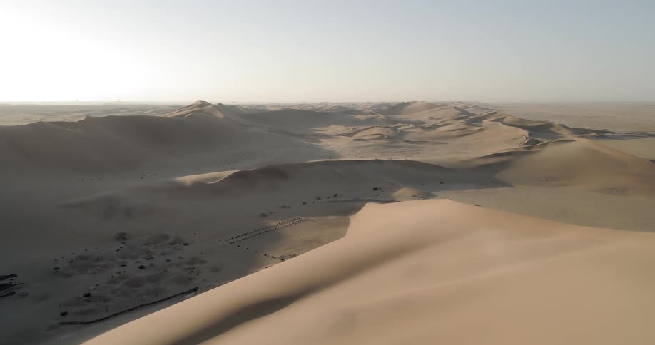A large desert contains a series of numerous sand dunes that reach the horizon