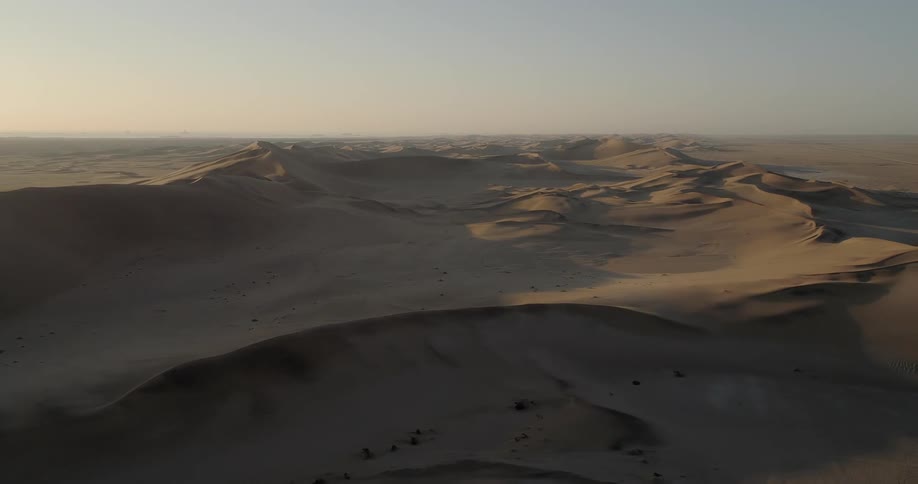 Dunes cast shadows on desert under clear blue sky