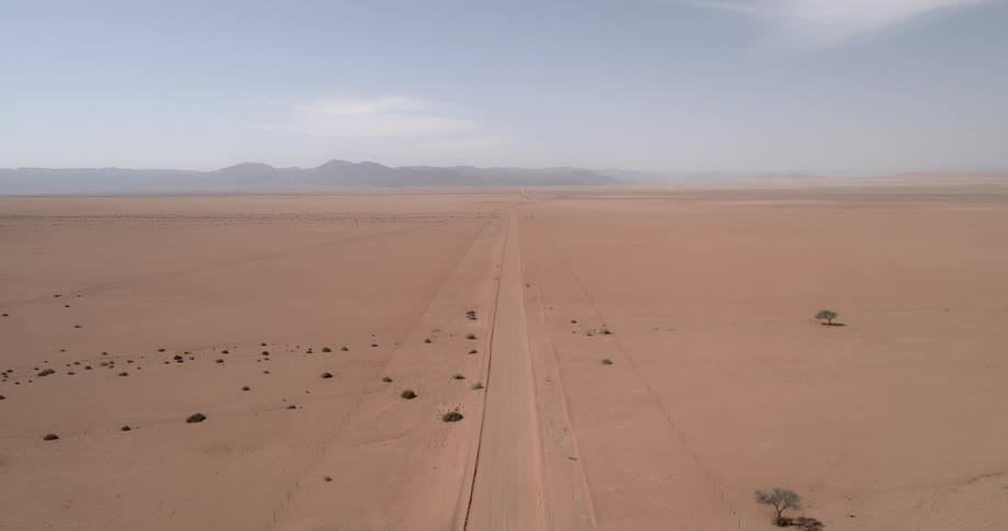 A dirt road in the desert with mountains in the background