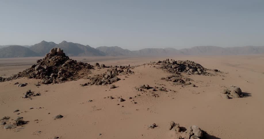 Large cluster of stones form an island in the middle of an expanse of red sand