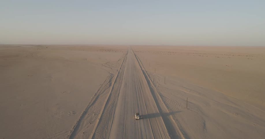 An aerial view of a car traveling on a desert road