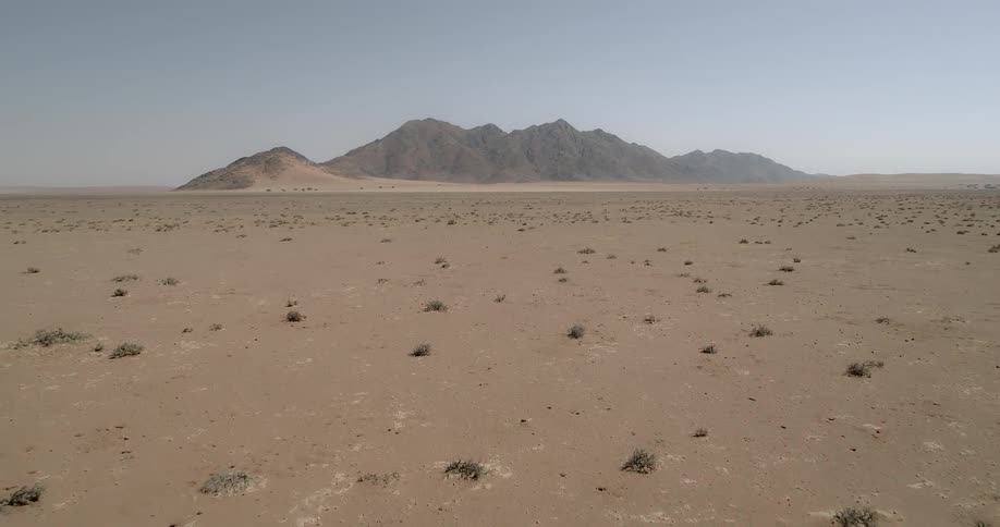 A desert with a mountain and the sky in the background