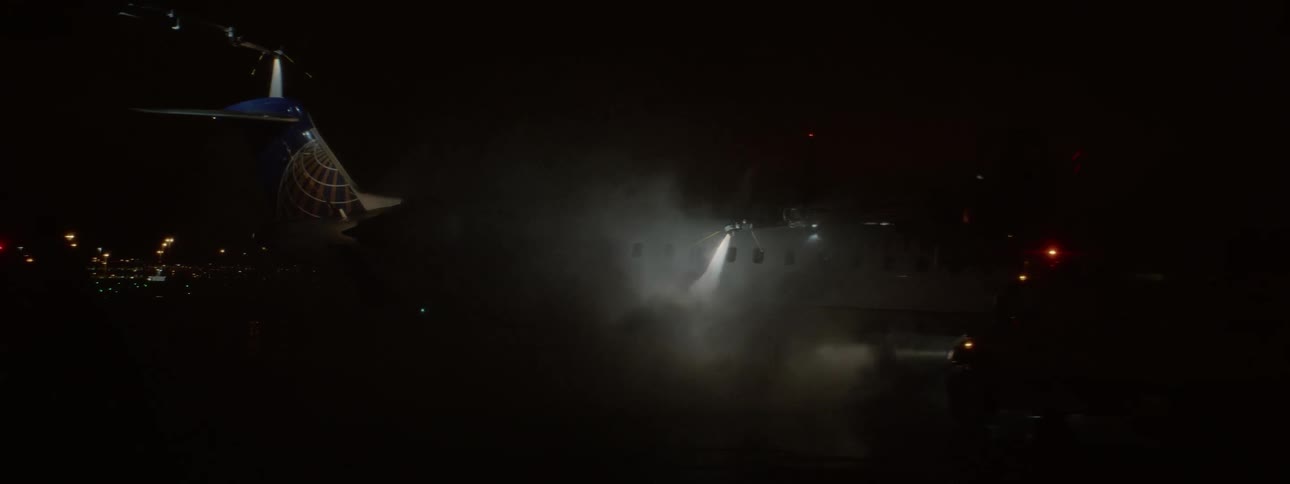 An airplane is being sprayed by something on a runway at night
