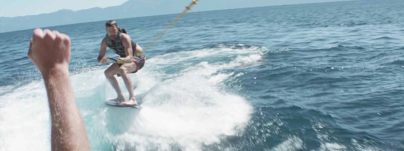 A man wakeboards on a lake on a sunny summer day