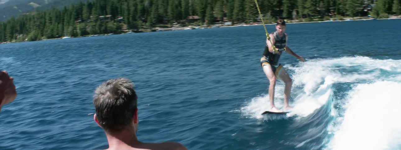 A person rides a wake board behind a boat